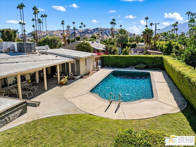 view of pool with central AC unit, a mountain view, a patio, and a lawn