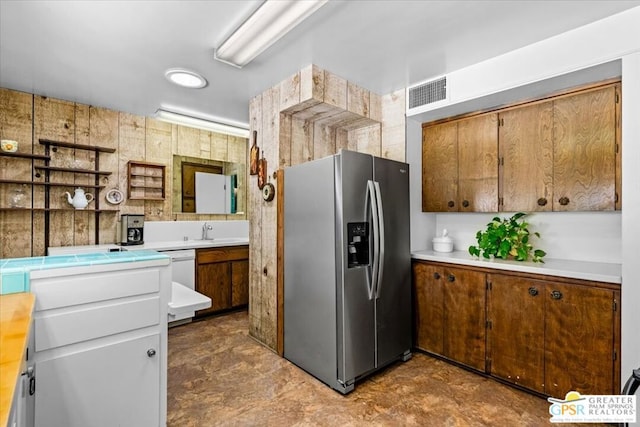 kitchen featuring stainless steel refrigerator with ice dispenser, white dishwasher, and sink