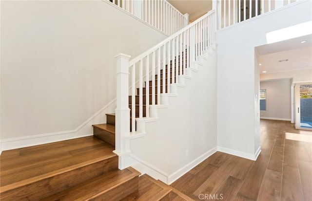 stairway with hardwood / wood-style floors and a high ceiling