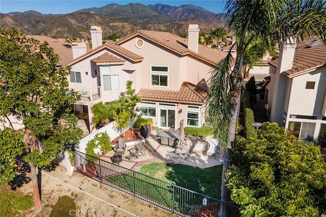 back of property with a mountain view and a patio