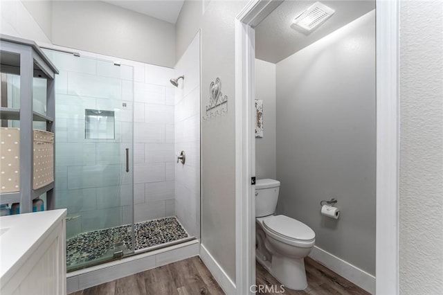 bathroom featuring hardwood / wood-style flooring, vanity, toilet, and a shower with shower door