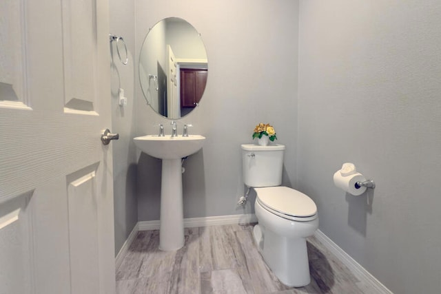 bathroom featuring toilet, wood-type flooring, and sink