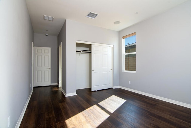 unfurnished bedroom with dark hardwood / wood-style flooring and a closet