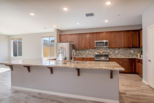 kitchen featuring a kitchen breakfast bar, sink, a spacious island, and appliances with stainless steel finishes