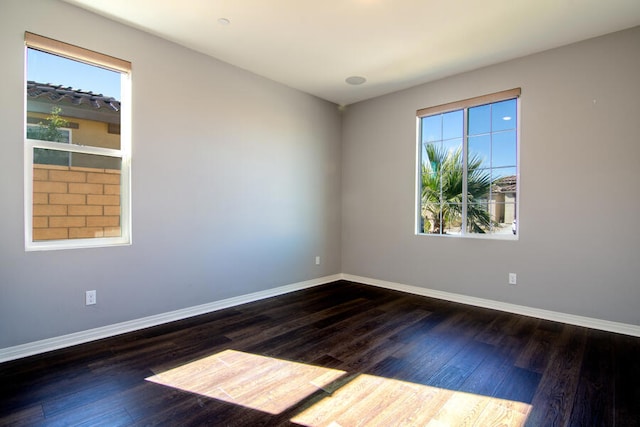 empty room with dark hardwood / wood-style flooring and a healthy amount of sunlight