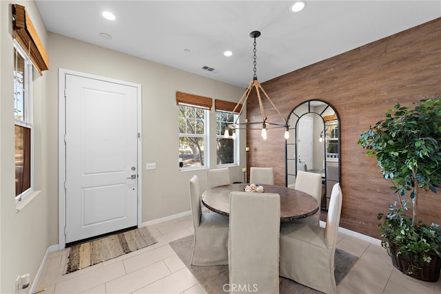 dining room featuring light tile patterned floors and wood walls