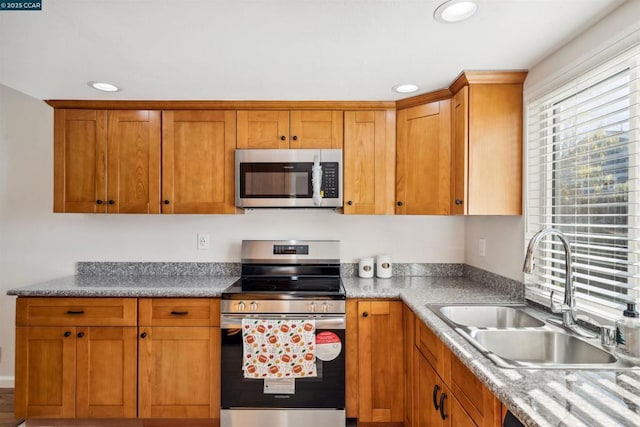 kitchen featuring stainless steel appliances, light stone countertops, and sink