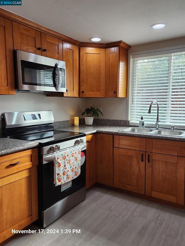 kitchen featuring appliances with stainless steel finishes, sink, and light hardwood / wood-style flooring