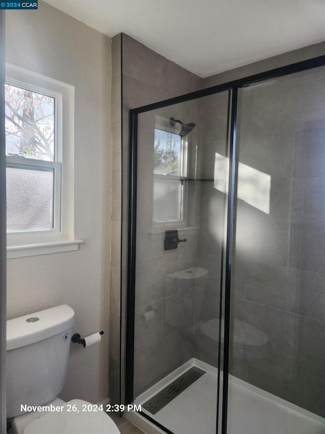 bathroom with toilet and a shower with shower door