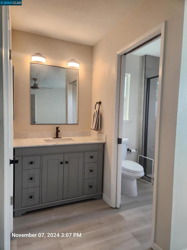 bathroom with vanity, ceiling fan, wood-type flooring, and toilet