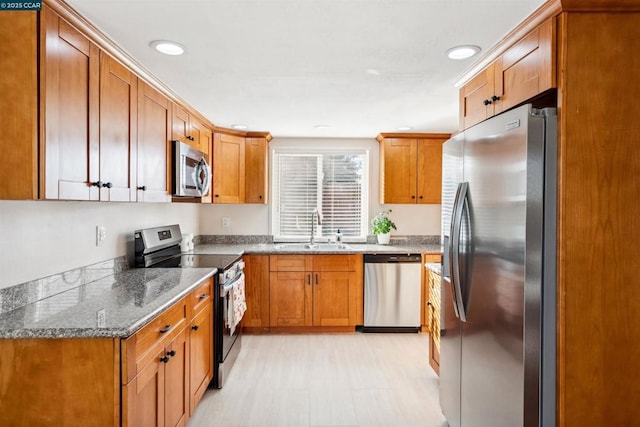 kitchen featuring stone countertops, appliances with stainless steel finishes, and sink