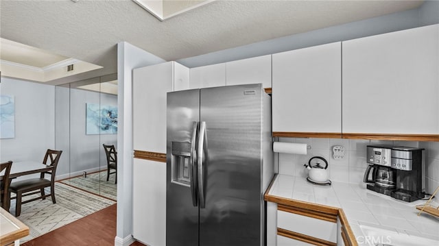 kitchen featuring white cabinetry, tile counters, stainless steel fridge with ice dispenser, a textured ceiling, and light wood-type flooring