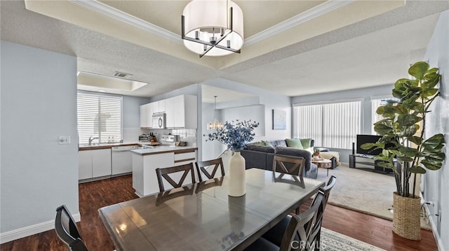 dining room featuring ornamental molding, a textured ceiling, a tray ceiling, an inviting chandelier, and dark hardwood / wood-style floors