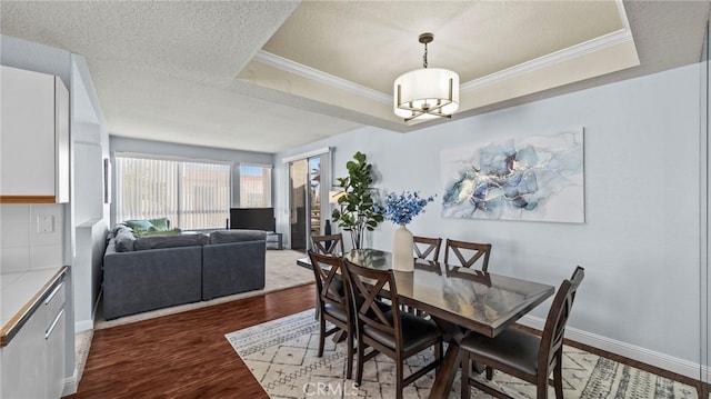 dining space featuring a tray ceiling, ornamental molding, dark hardwood / wood-style floors, and an inviting chandelier