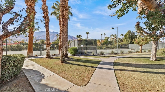 view of home's community featuring a mountain view, tennis court, and a yard