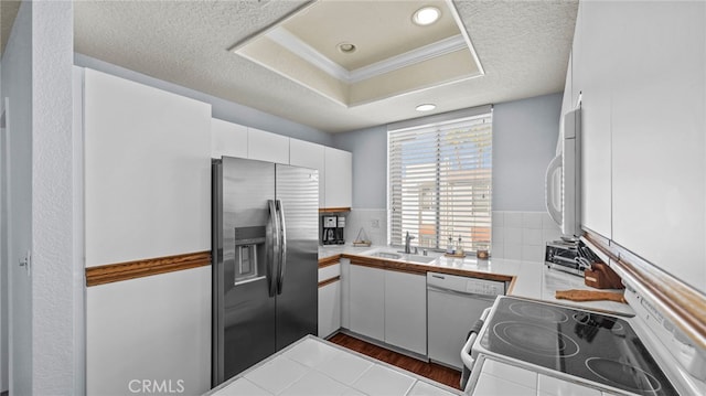 kitchen with sink, tile countertops, wood-type flooring, white appliances, and white cabinets