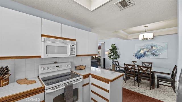 kitchen with white cabinets, tile counters, pendant lighting, and white appliances