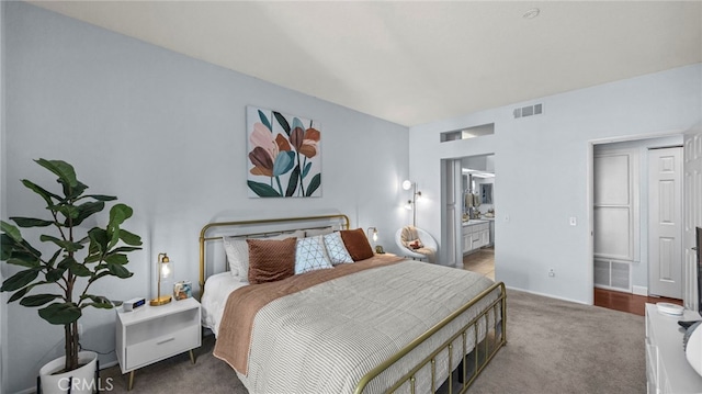 bedroom with ensuite bathroom and carpet floors