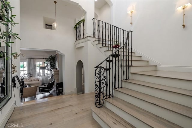 stairs with wood-type flooring and a towering ceiling