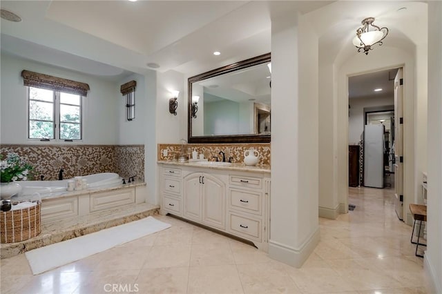 bathroom featuring backsplash, vanity, and a tub to relax in