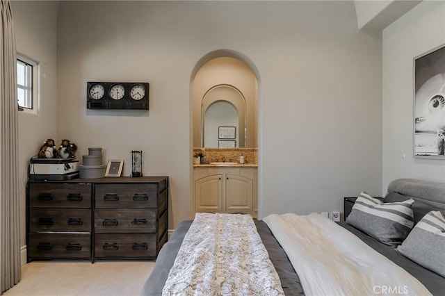 bedroom featuring ensuite bath, light carpet, and sink