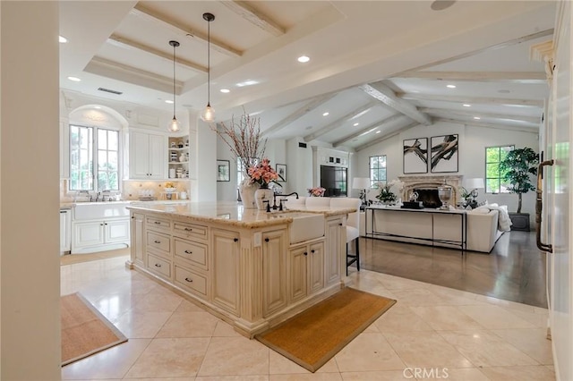 kitchen with light stone countertops, sink, pendant lighting, a breakfast bar, and a center island with sink