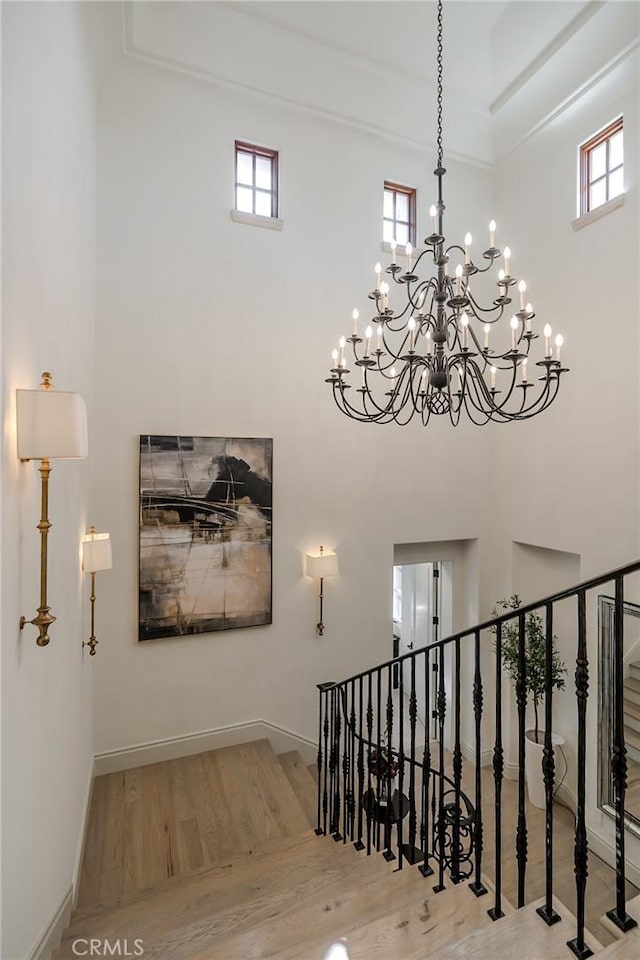 staircase featuring a towering ceiling, an inviting chandelier, and hardwood / wood-style flooring