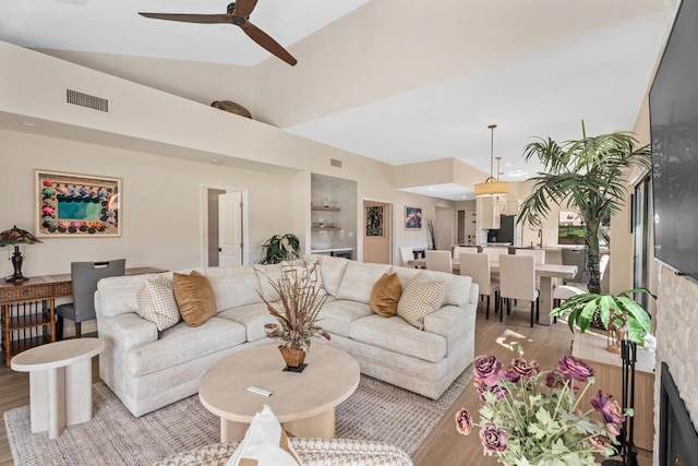 living room with ceiling fan, vaulted ceiling, and light hardwood / wood-style flooring