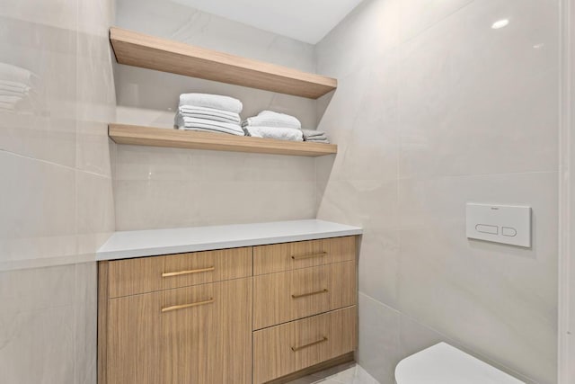 bathroom with vanity, tile walls, and toilet