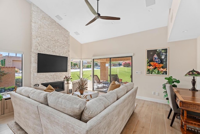 living room with ceiling fan, a fireplace, high vaulted ceiling, and light hardwood / wood-style floors