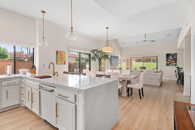 kitchen featuring sink, white cabinets, light hardwood / wood-style floors, and decorative light fixtures