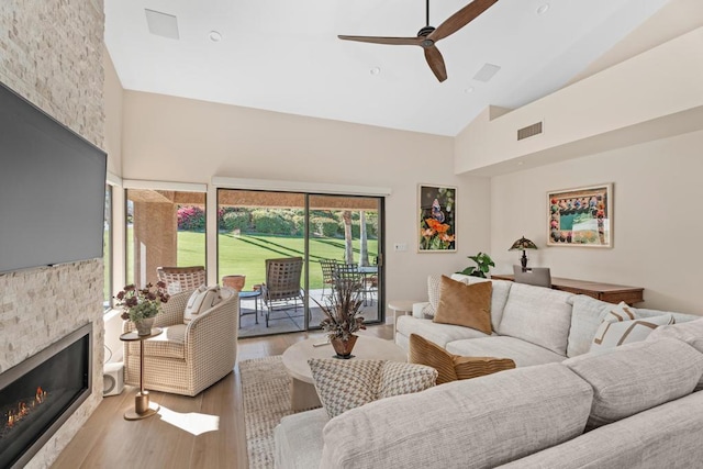 living room featuring a fireplace, hardwood / wood-style floors, high vaulted ceiling, and ceiling fan