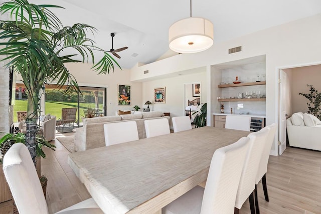 dining room featuring ceiling fan, light hardwood / wood-style flooring, and high vaulted ceiling