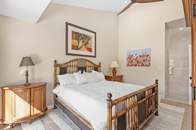 bedroom featuring ensuite bathroom, light hardwood / wood-style floors, ceiling fan, and vaulted ceiling