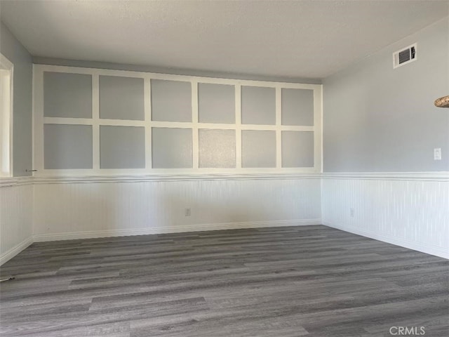 unfurnished room with built in features, a textured ceiling, and dark hardwood / wood-style flooring