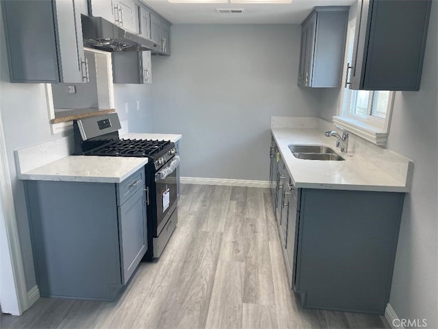 kitchen with gas range, sink, gray cabinets, and light hardwood / wood-style floors