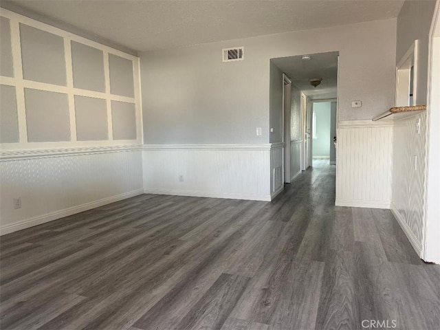 empty room with a textured ceiling and dark hardwood / wood-style floors