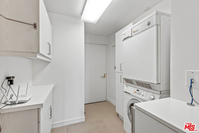 washroom featuring cabinets and stacked washer / dryer