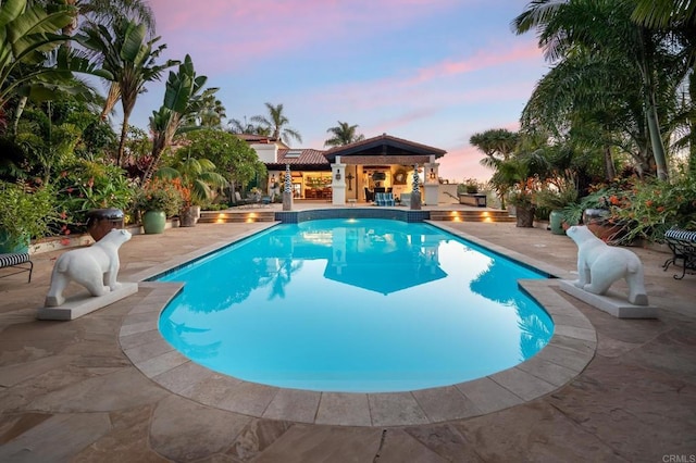 pool at dusk with a patio area