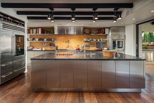 kitchen with a sink, dark stone countertops, beamed ceiling, decorative backsplash, and open shelves