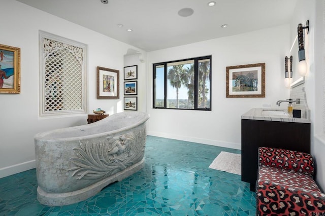 bathroom with baseboards, a freestanding tub, recessed lighting, and vanity