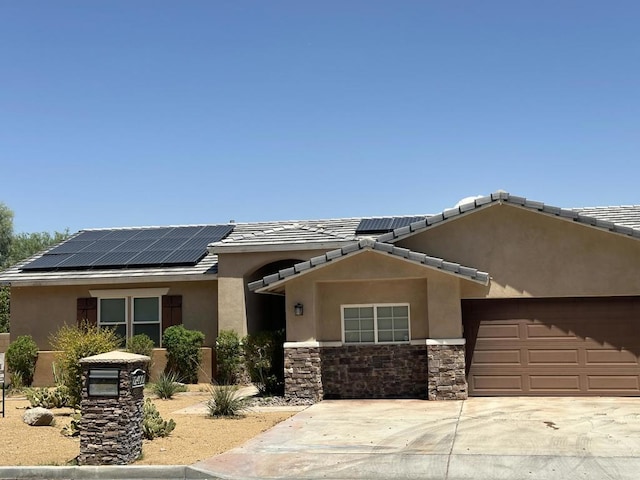 ranch-style home featuring solar panels and a garage