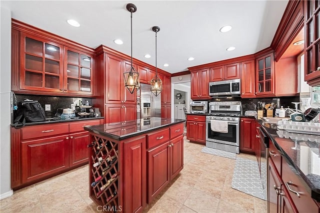 kitchen with appliances with stainless steel finishes, backsplash, a kitchen island, and hanging light fixtures