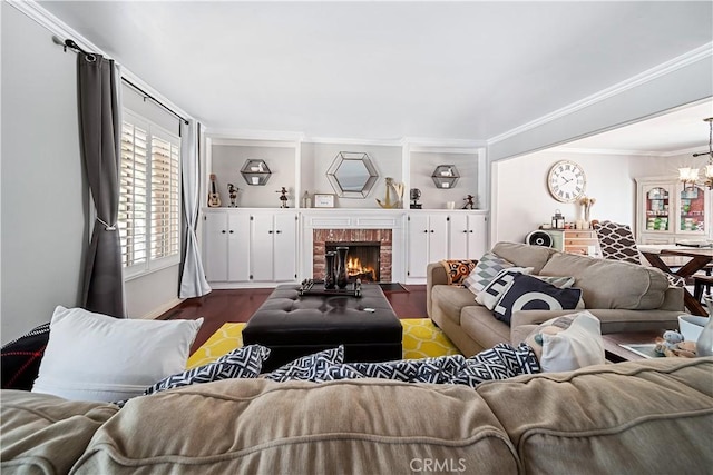 living room featuring crown molding, an inviting chandelier, dark hardwood / wood-style floors, and a brick fireplace