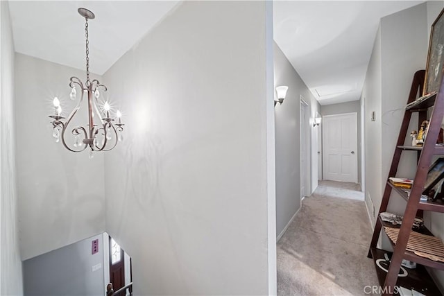 hallway with light carpet and a notable chandelier