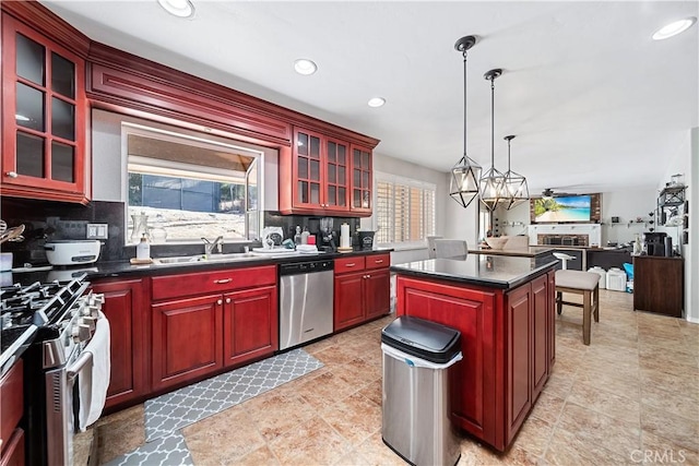 kitchen with tasteful backsplash, stainless steel appliances, sink, decorative light fixtures, and a kitchen island