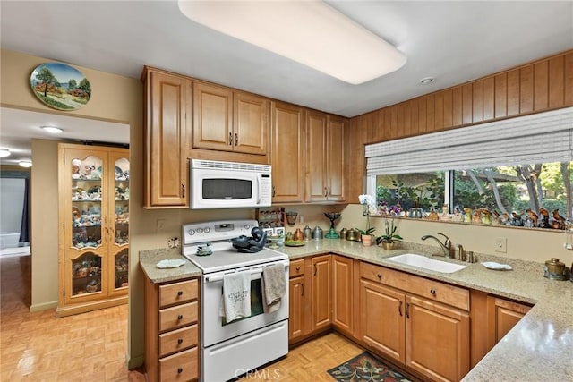 kitchen featuring light stone counters, sink, light parquet floors, and white appliances