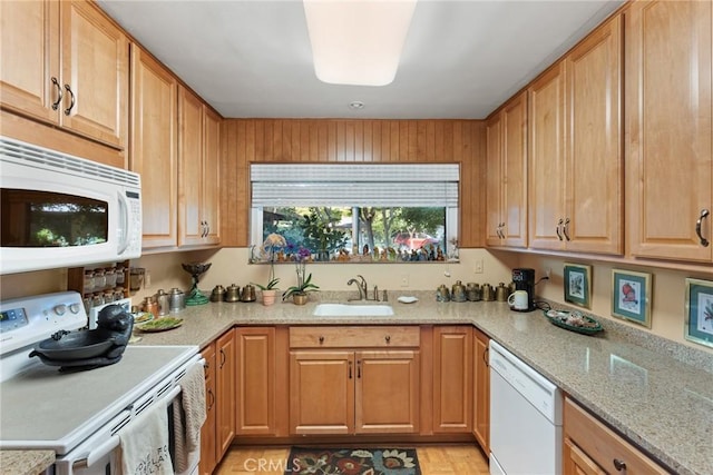 kitchen with light stone counters, sink, and white appliances