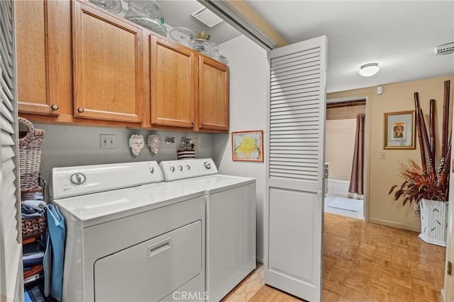 clothes washing area featuring separate washer and dryer, light parquet flooring, and cabinets