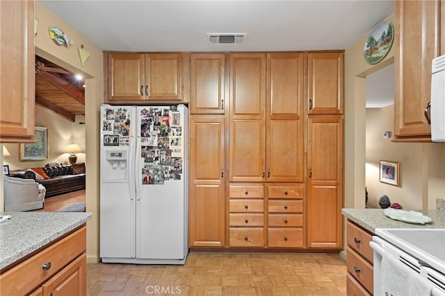 kitchen with light stone countertops, light parquet flooring, and white appliances